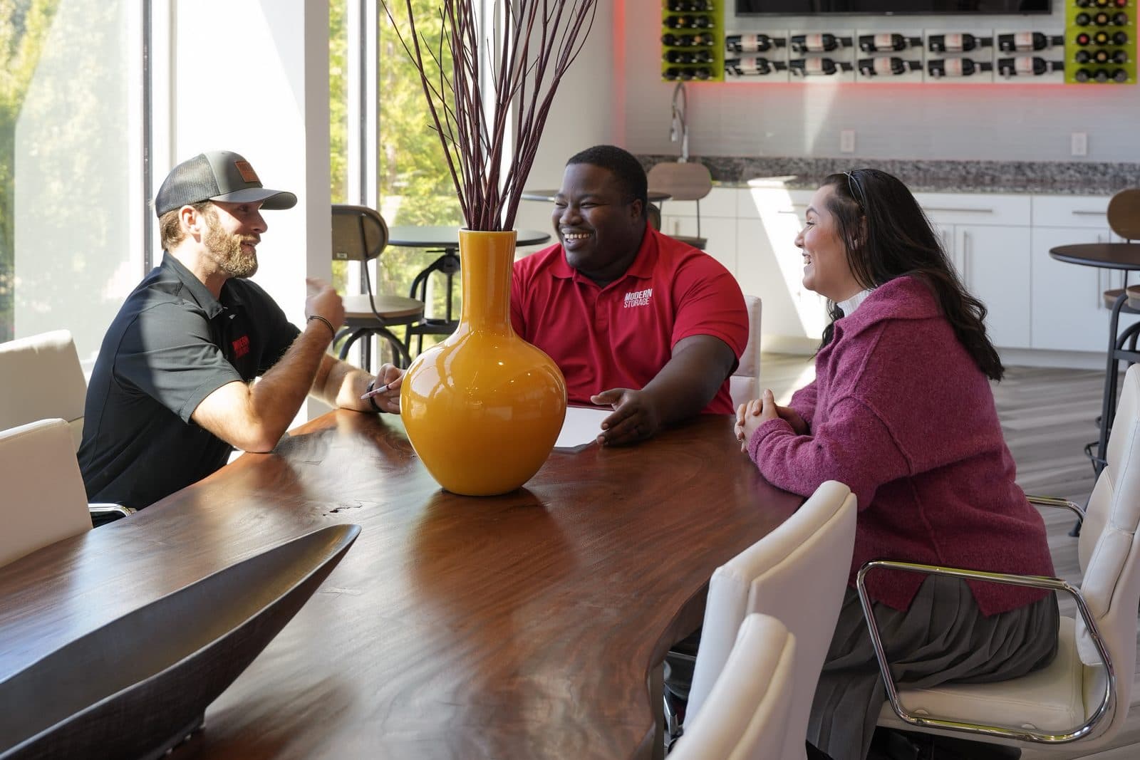 Modern Storage® team members in branded polos talking together around a conference table