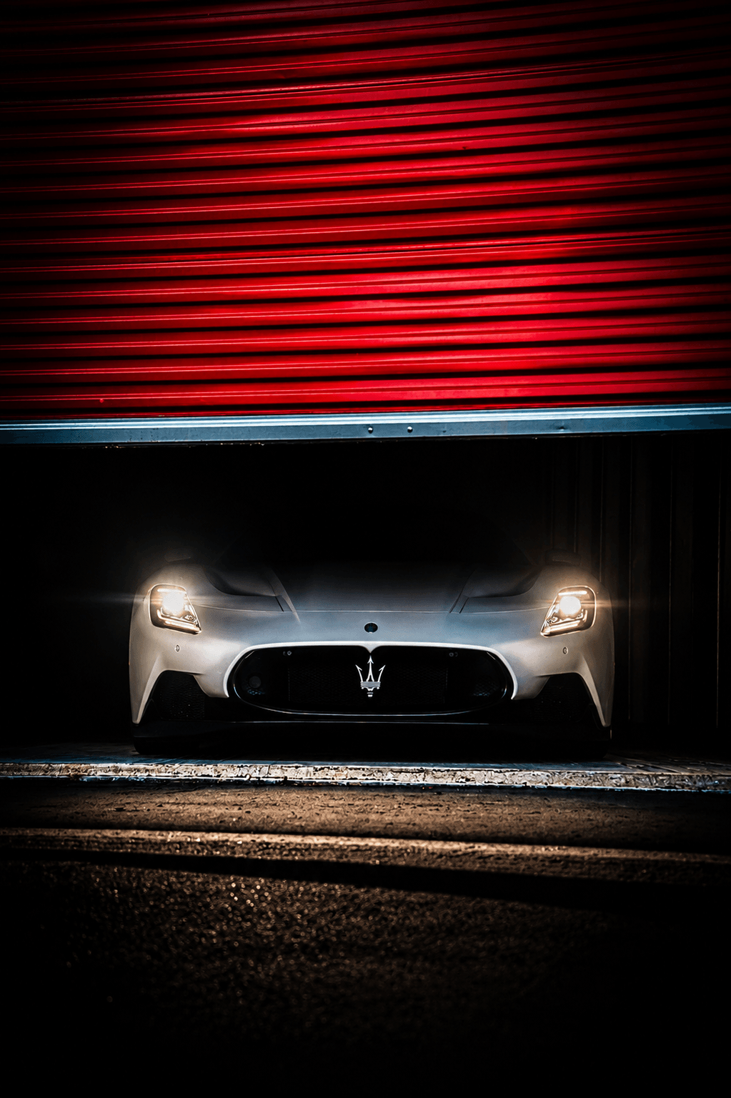 Exotic car emerging from a red Modern Storage® roll-up door — indoor enclosed vehicle storage in Arkansas