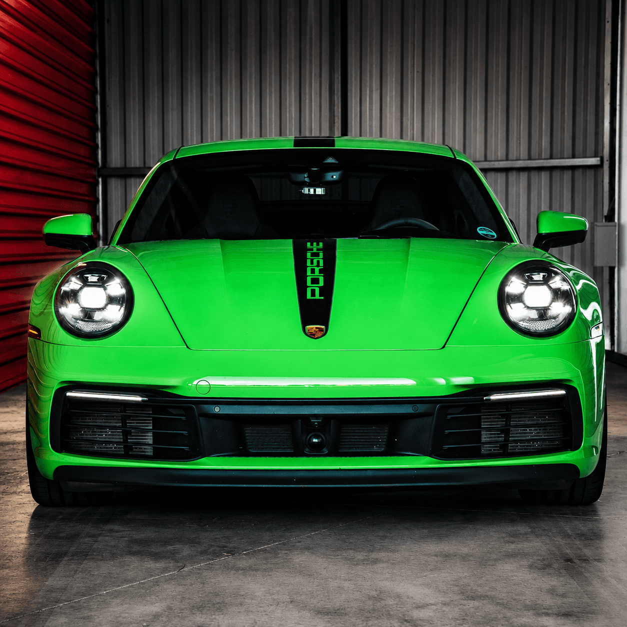 Silver Porsche 911 parked in golden-hour light against Modern Storage® red roll-up doors — Arkansas collector and exotic car storage
