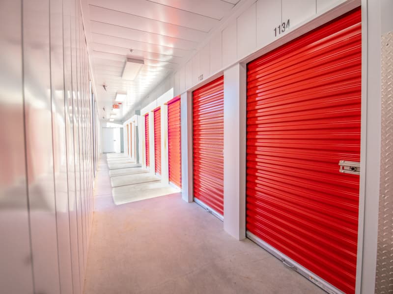 A clean, well-lit hallway of red roll-up self-storage units at Modern Storage®, ideal for household, seasonal, or business use.