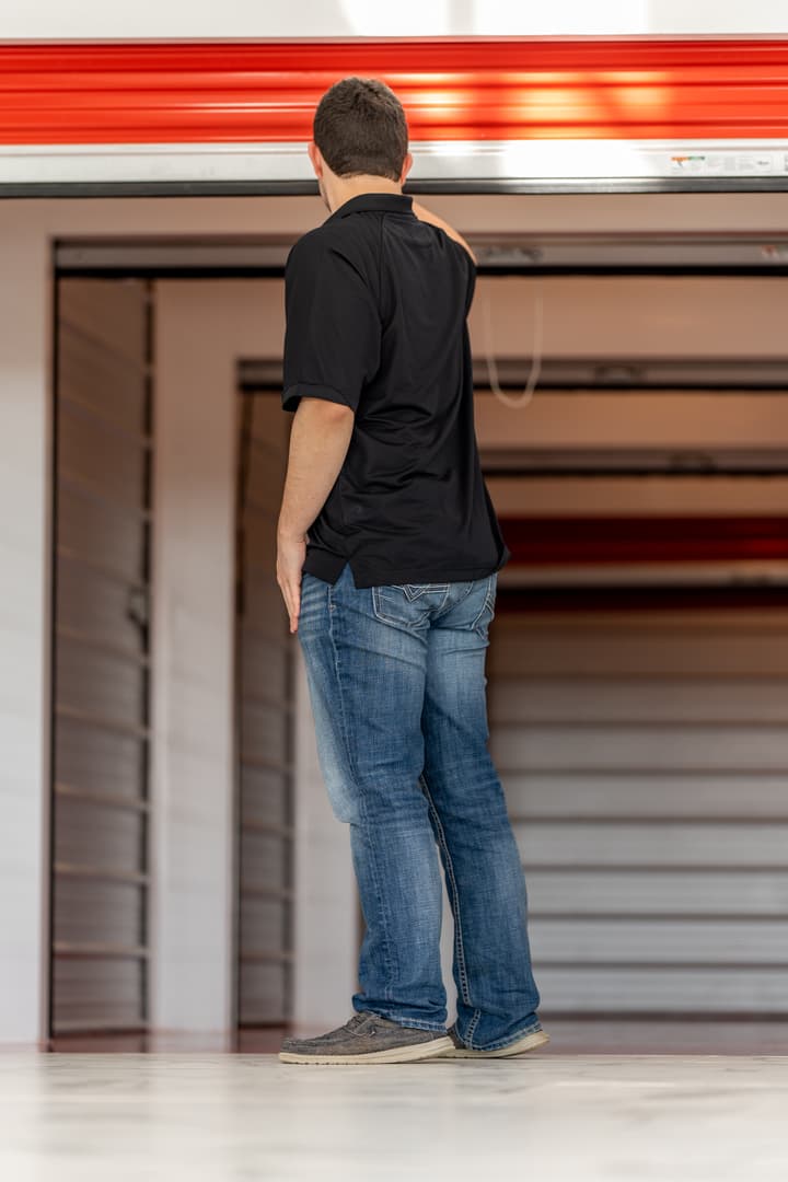 A man stands in front of an open Modern Storage® unit, packing boxes into the space, representing how to choose the right self-storage size for your needs.