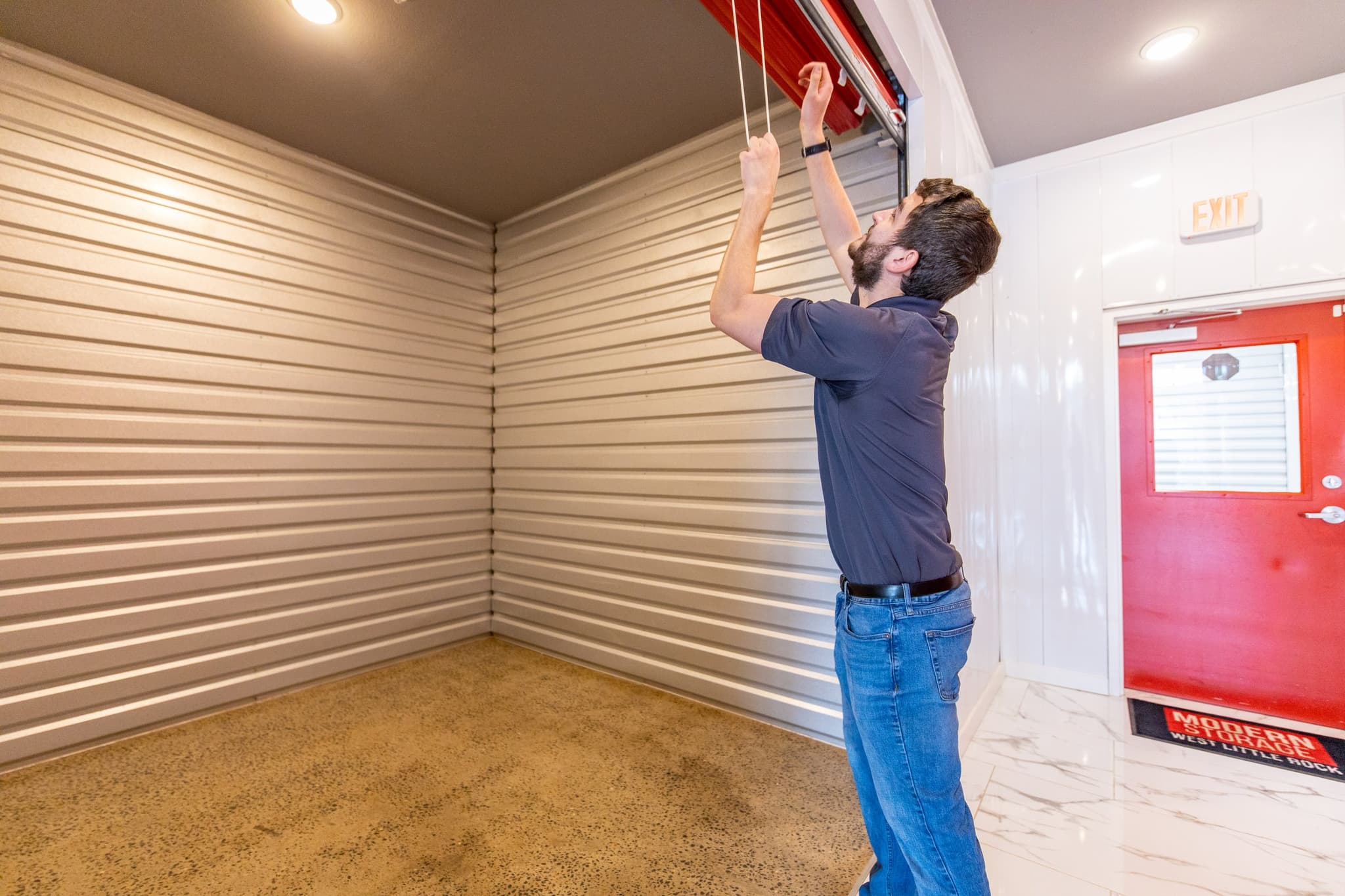 A man opens a clean, empty Modern Storage unit inside a facility, showcasing interior dimensions to help customers visualize the right storage size for their needs.