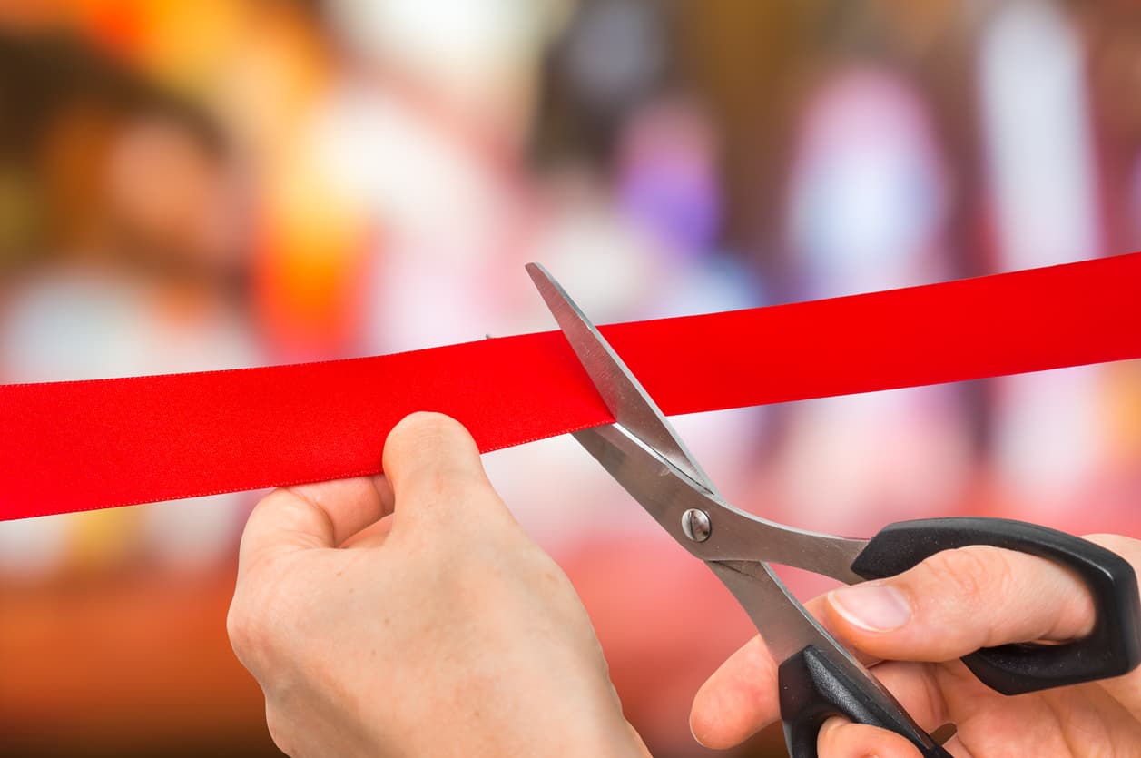 Close-up of a person cutting a red ribbon with scissors during a Modern Storage® grand opening ceremony