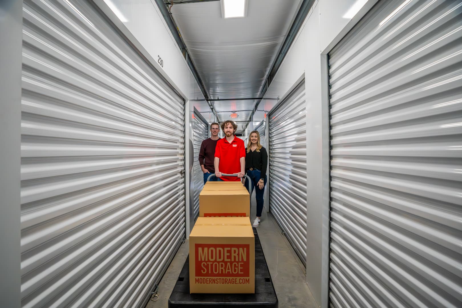 Modern Storage® people pushing a cart with branded boxes through a climate-controlled hallway