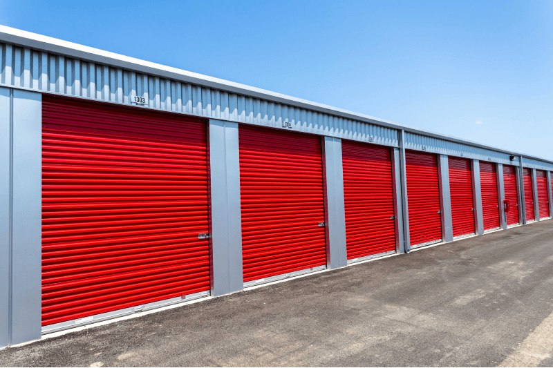 Row of bright red drive-up storage unit doors at Modern Storage Bentonville under a clear blue sky