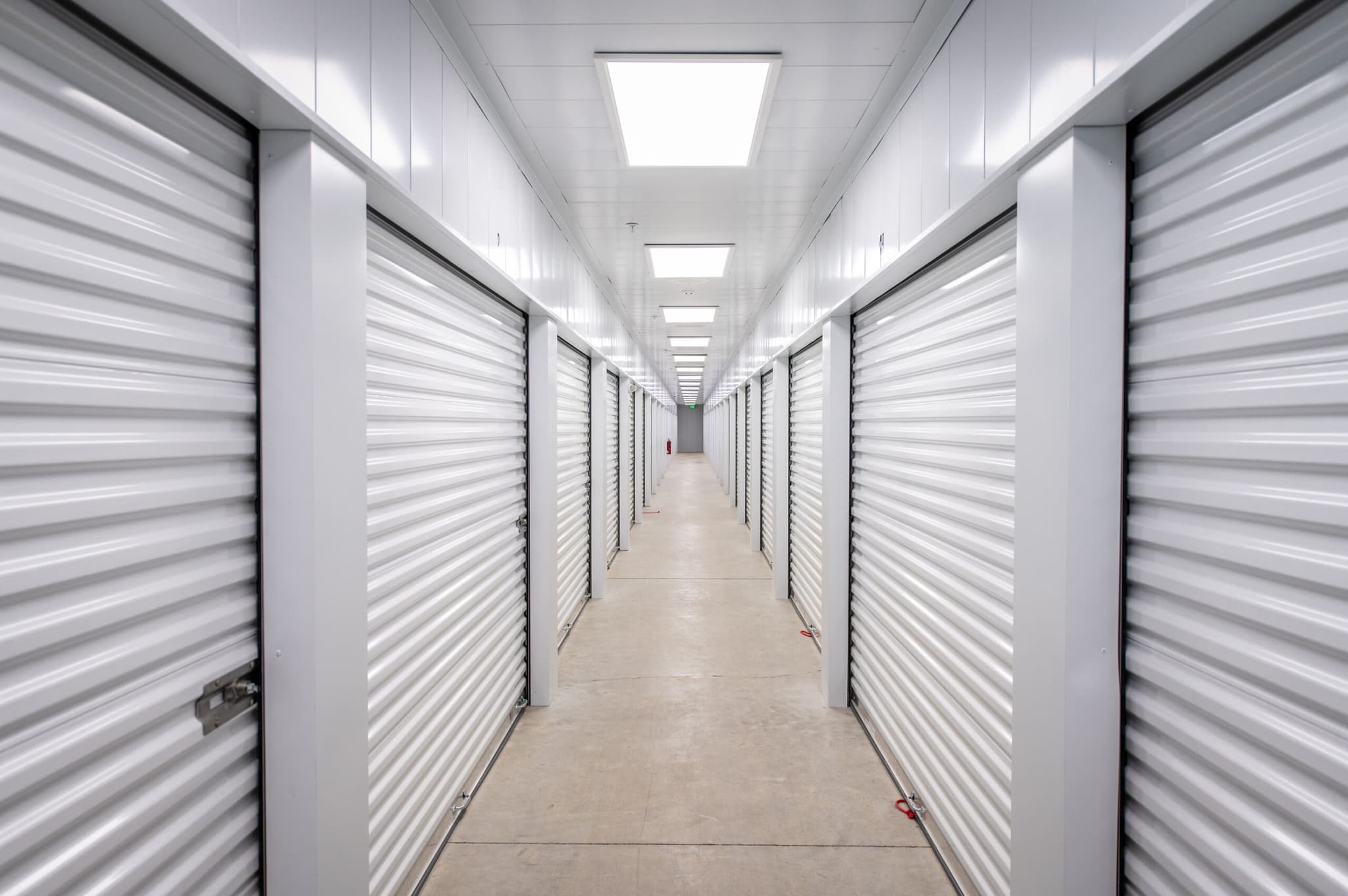 Clean, well-lit indoor hallway with white roll-up storage doors at Modern Storage® facility