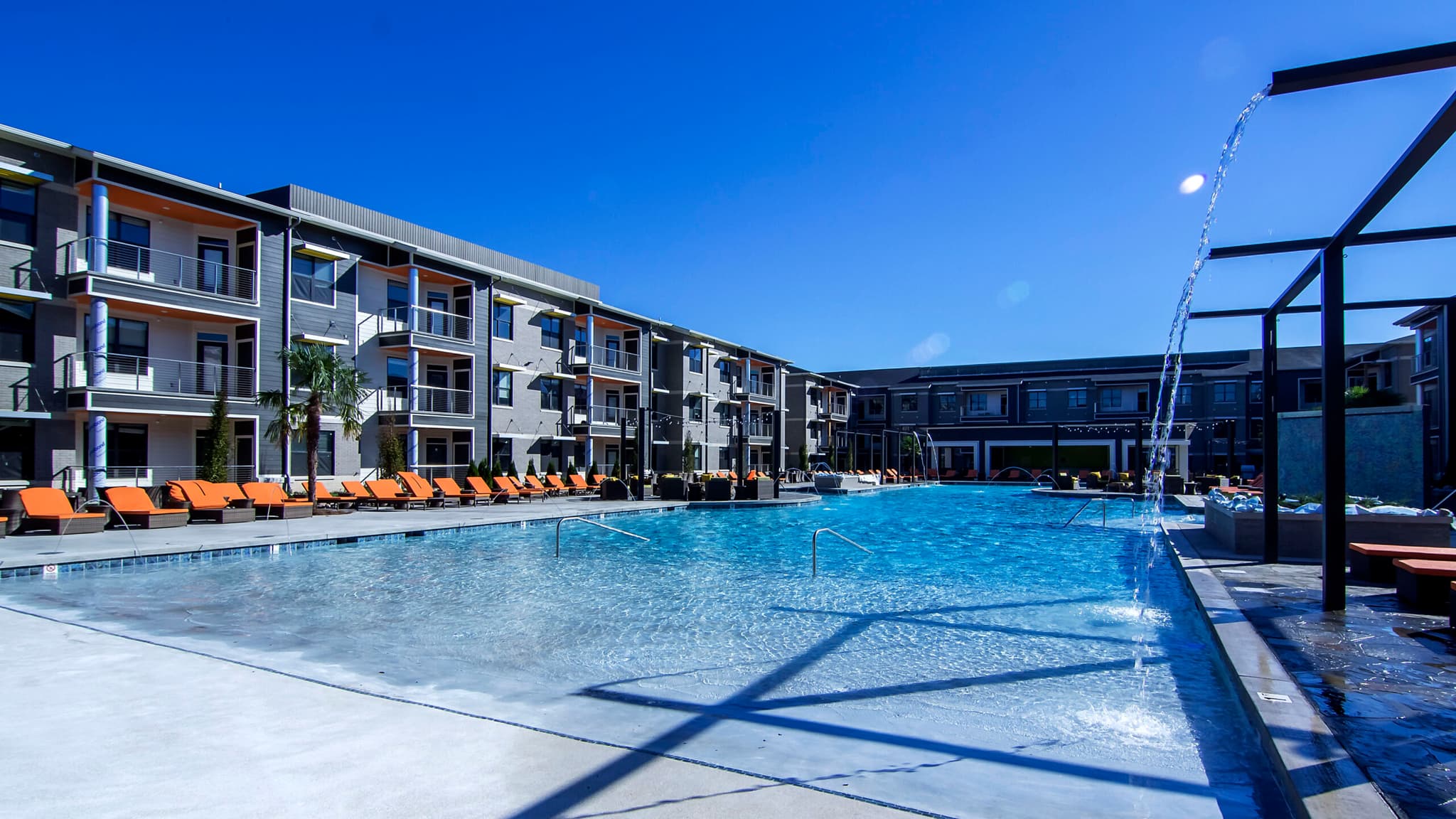 Sparkling outdoor swimming pool surrounded by modern apartment buildings under a clear blue sky at a luxury West Little Rock