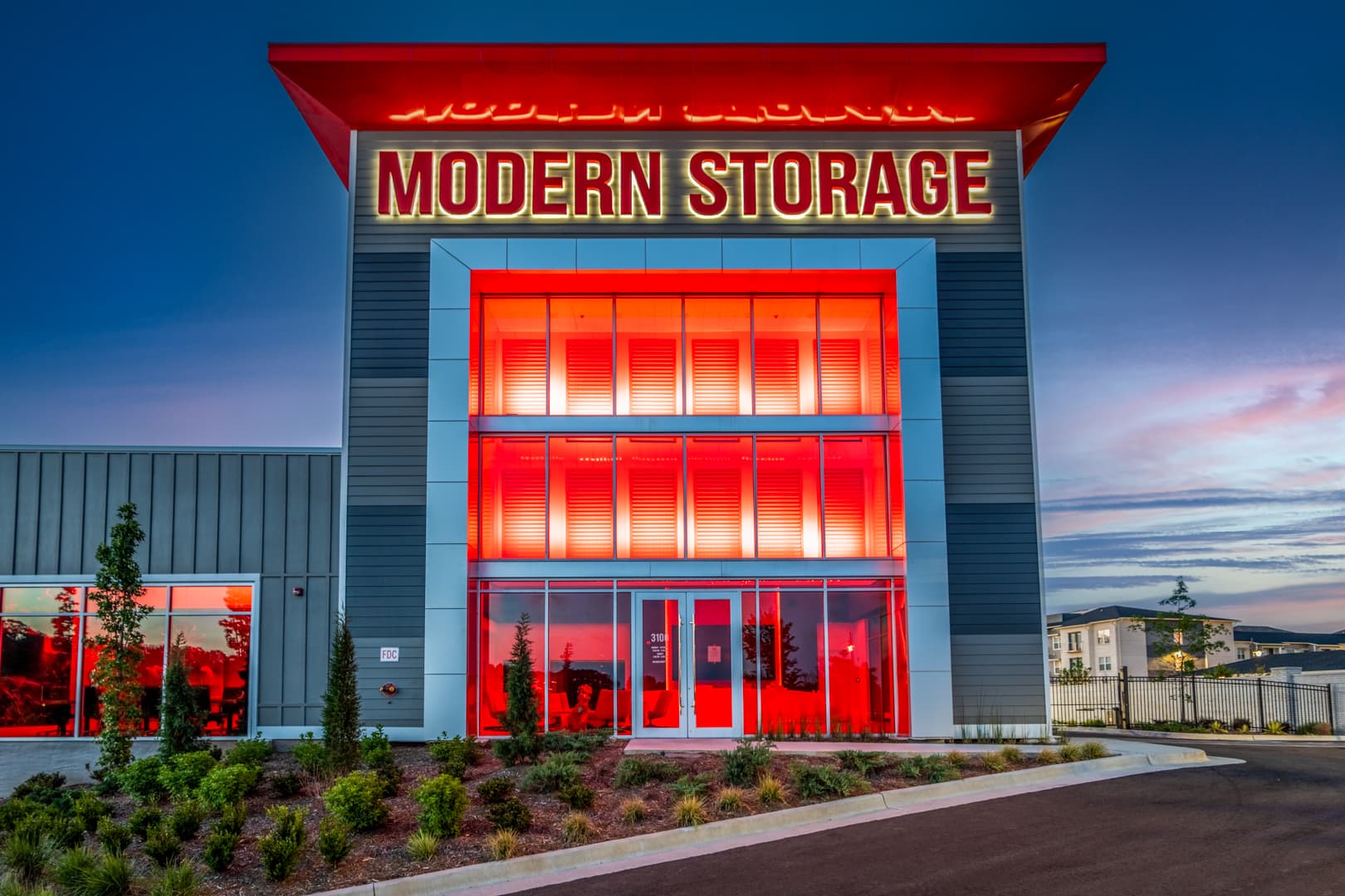Modern Storage® North Little Rock facility illuminated at night with glowing red lights, sleek architectural facade, and land