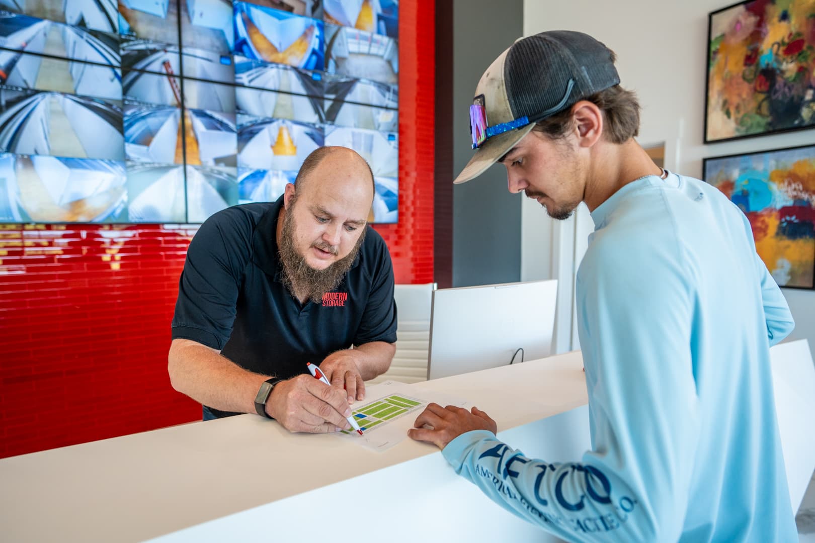 Modern Storage® employee assists new tenant with signing lease paperwork at front desk