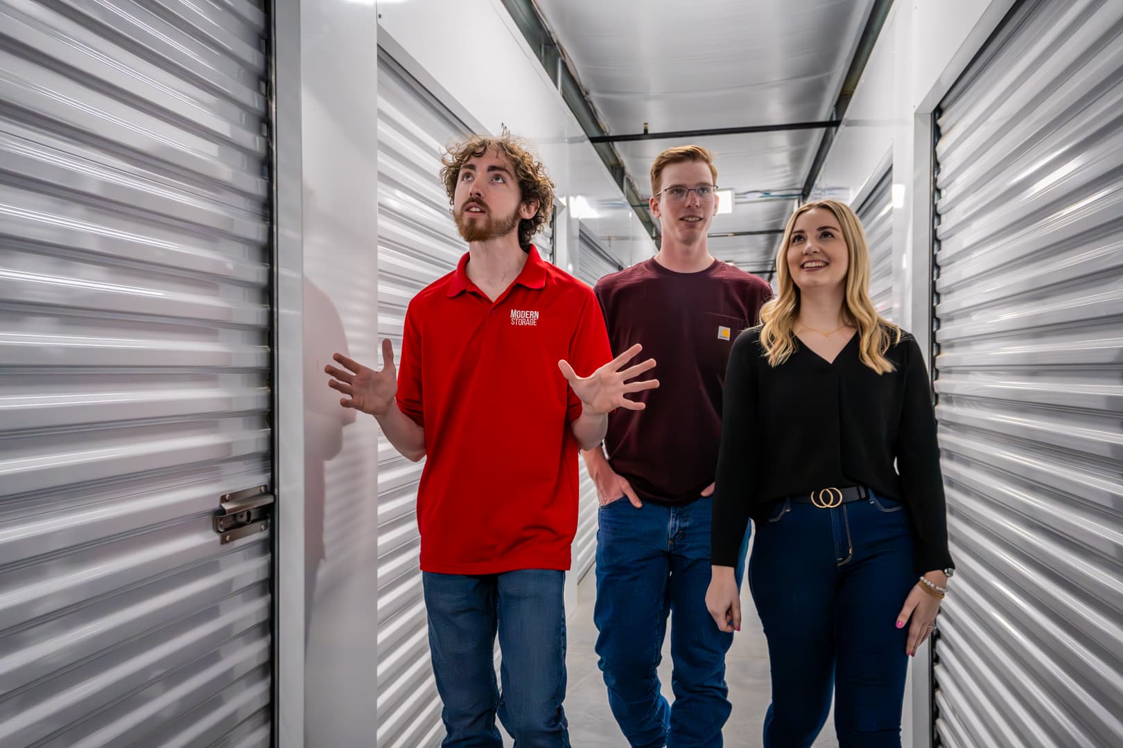 Modern Storage® Shackleford team member giving a tour to two tenants inside a brightly lit, climate-controlled hallway lined