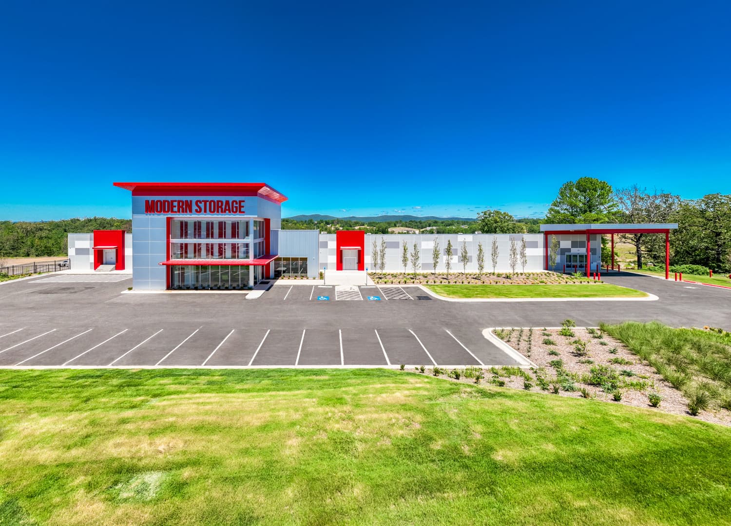 Front view of Modern Storage® facility with red and gray exterior and clear blue sky