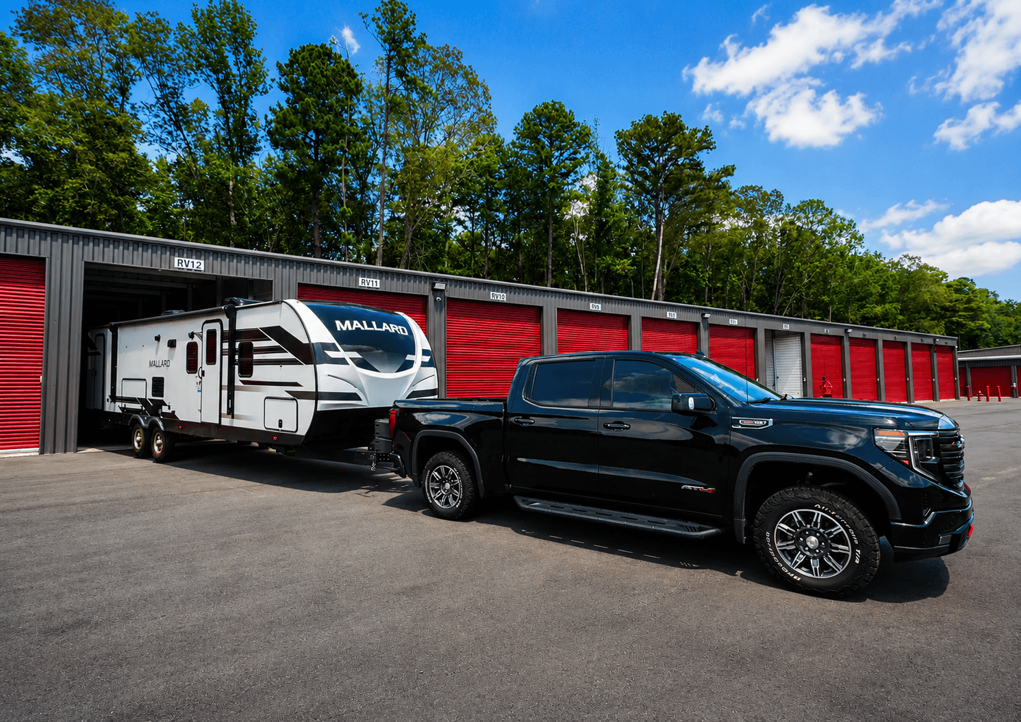 Pickup truck towing a travel trailer into an enclosed RV storage unit at Modern Storage in Arkansas.