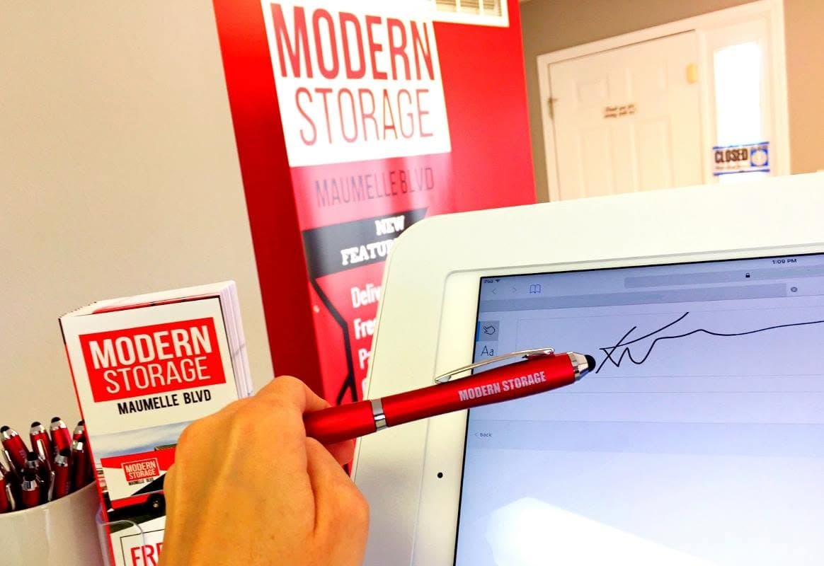 Customer signing a storage rental agreement at the Modern Storage office with online rental options available.